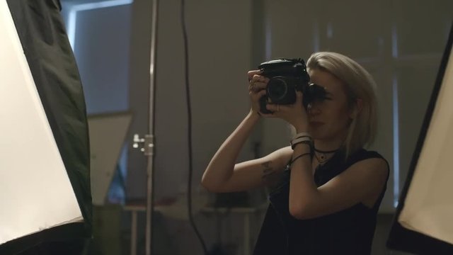 Young female fashion photographer taking photos at studio 