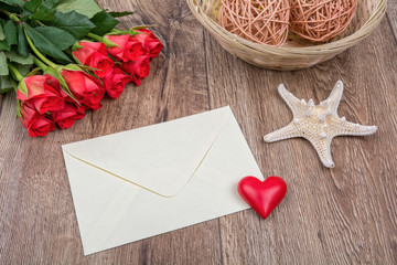 Envelope, roses and starfish on a wooden background