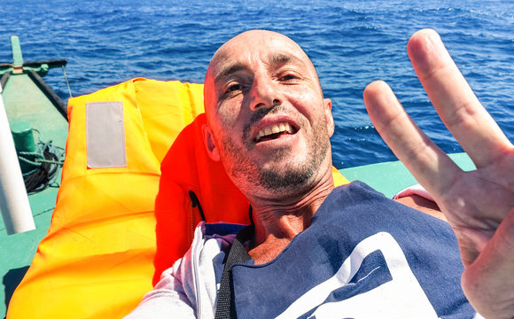 Man taking selfie on solo ocean crossing tropical  - Tired male survivor to extreme travel experience - Concept of hard sea travel or clandestine migrant mediterranean trip