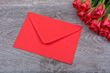 Red envelope and roses on a wooden background