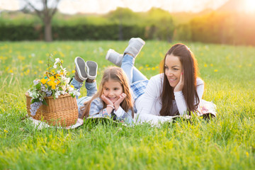 Beautiful young mother with her five years old daughter laying on the grass,colored photo
