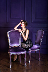 Obraz premium Young sitting on a chair and looking on camera in a purple inter
