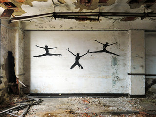 Three ballerina silhouettes on vintage old wall inside abandoned building
