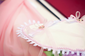 wedding ring on a pink pillow