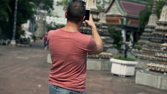 Young man taking photo of temple in Bangkok, Thailand
