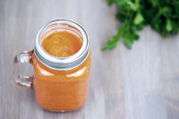 Healthy carrot smoothie in a jar on wooden background with parsley. Cold toning. Shallow dof