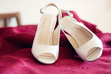 white wedding shoes of the bride on lilac fabric