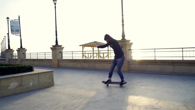 skateboarder doing trick on the embankment at dawn slow motion