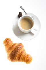 Top view of cup of coffee with croissant on white background