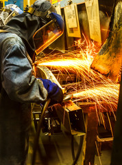 The worker grinding metal in manufacturing plant