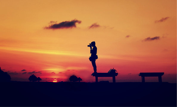 The silhouette of photographer with sunset background