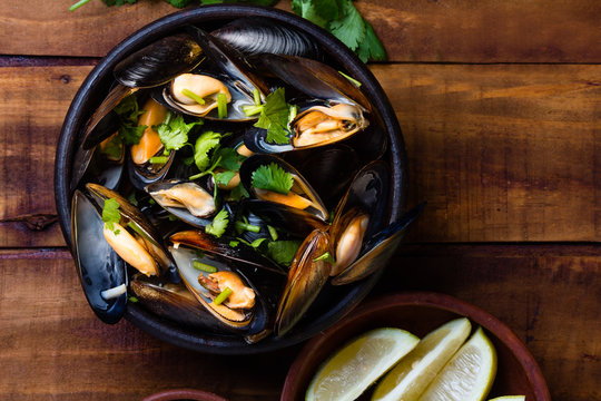 Mussels in clay bowl on wooden dark background