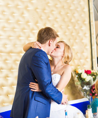 stylish gorgeous happy bride and groom kissing at wedding reception, emotional cheerful moment