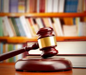 Judge gavel on wooden table on book shelves background