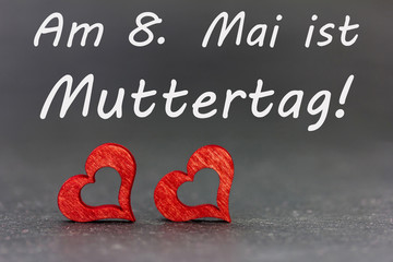 zwei Herzen und ein Text für den Muttertag vor dunklem Hintergrund
