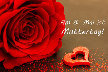 ein Herz, eine rote Rose und ein Text für den Muttertag liegen auf einer Tafel