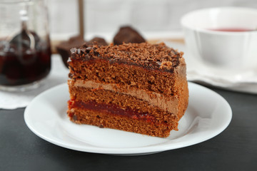 Sliced chocolate cake on wooden table, on light background