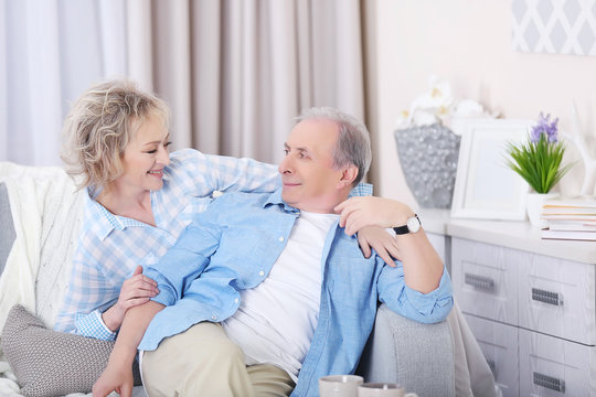 Mature couple sitting together  on a sofa at home