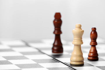 Chess pieces and game board on light blurred background