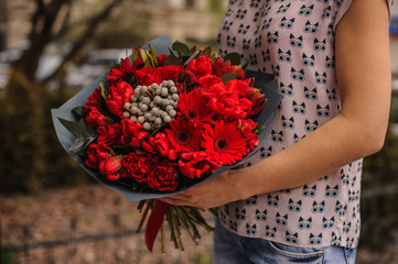 Fototapeta na wymiar beautiful bouquet of red flowers with black paper in hands