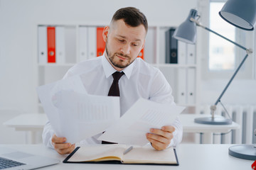 confused businessman examines documents