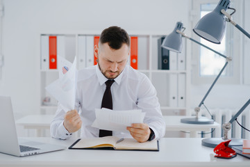 confused businessman examines documents