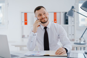 Businessman talking mobile phone in office and smile
