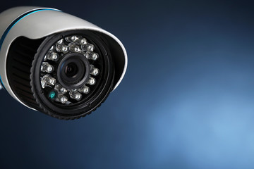 Security CCTV camera on blue background, closeup