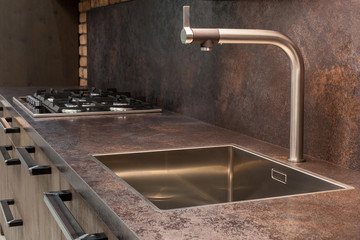 Modern designer chrome water tap over stainless steel kitchen sink.