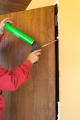 Construction builder works with polyurethane foam during frame insulation at door installation