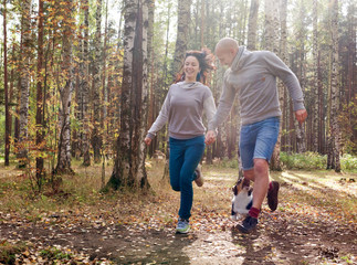 Couple running in the park with a Welsh Corgi Cardigan