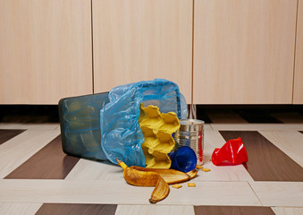 Full inverted garbage basket on kitchen floor