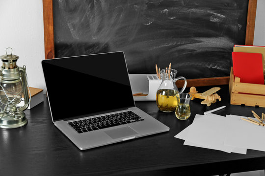 Desktop with notebook and other items on blackboard background