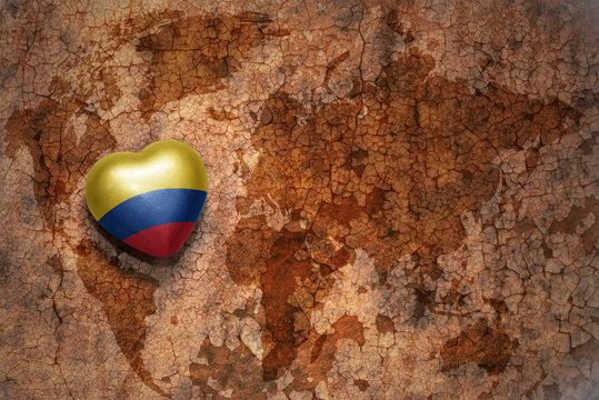 heart with national flag of colombia on a vintage world map crack paper background. concept
