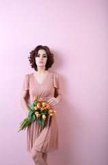 Woman in a pink dress with a bouquet of flowers.