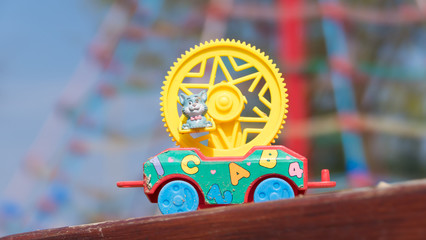 A detail of color plastic vehicle toy with yellow broken wheel and blue cat with butterfly during lovely spring time on the playground for kids - color toned image - focus on cat