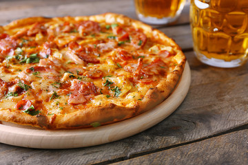 Delicious pizza  and glasses of beer are on wooden table, close up