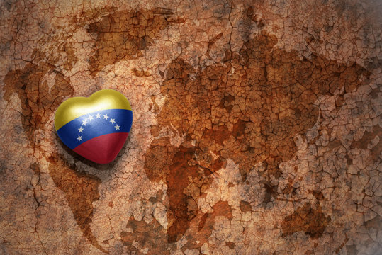 heart with national flag of venezuela on a vintage world map crack paper background. concept