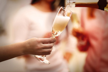 Pouring champagne into glass at hen-party, close up