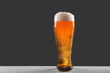 Glass of lager beer on grey background