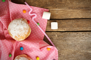 Delicious sugary donuts with pink napkin on wooden table, top view