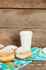 Delicious sugary donuts with blue napkin on wooden background