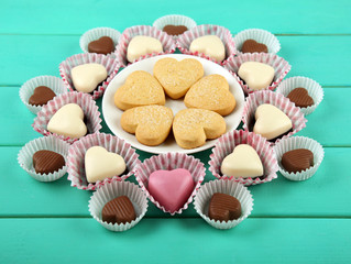 Valentine's Day concept. Composition of delicious chocolate candies and tasty cookies on turquoise wooden background