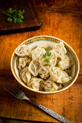 Dumplings with meat and vegetables in a vintage bowl on rustic wooden table