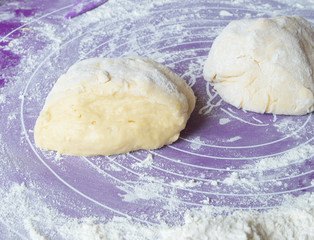 Homemade dough is cut in half on a floured surface.