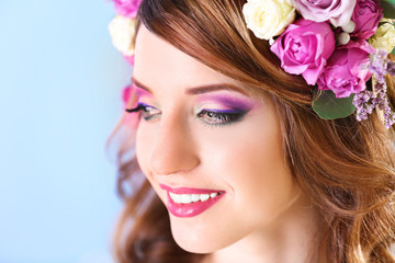 Obraz na płótnie Canvas Beautiful young woman wearing floral headband on a blue background