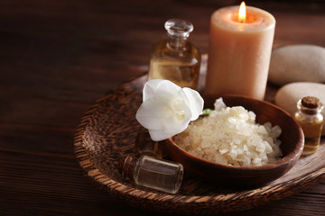 Spa set with sea salt, exotic flowers and candles on wicker tray