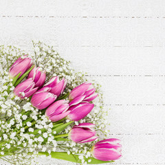 Pink tulips and gypsophila flowers on white tablecloth. Bouquet, top view, copy space, holiday background