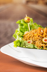 Classy presentation salad, rice and olives in artistic white plate with abstract background