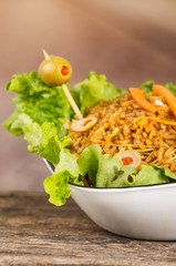 Closeup classy presentation salad, rice and olives in artistic white plate with abstract background